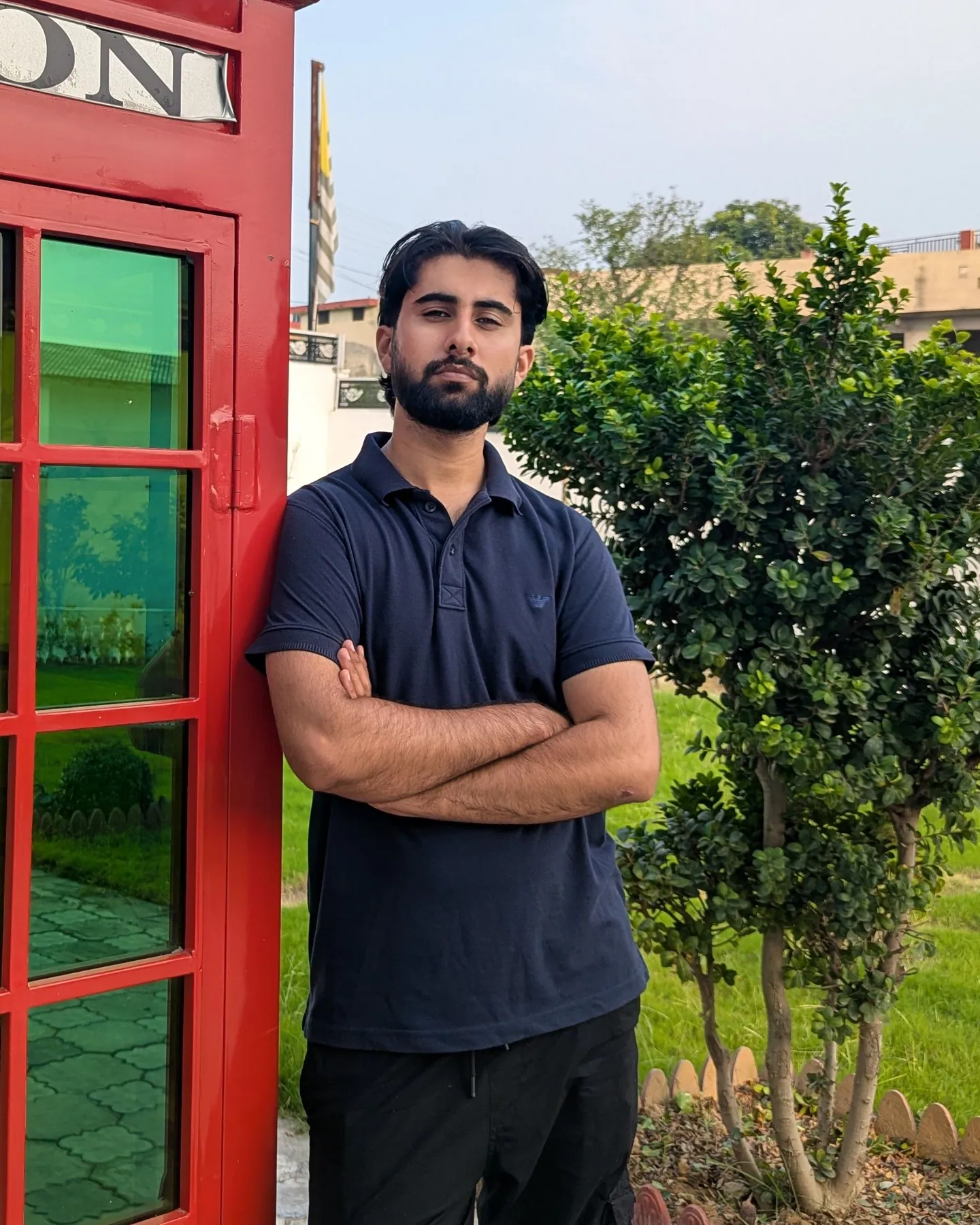 Muhammad Kaif leaning against a red London phone box, arms crossed