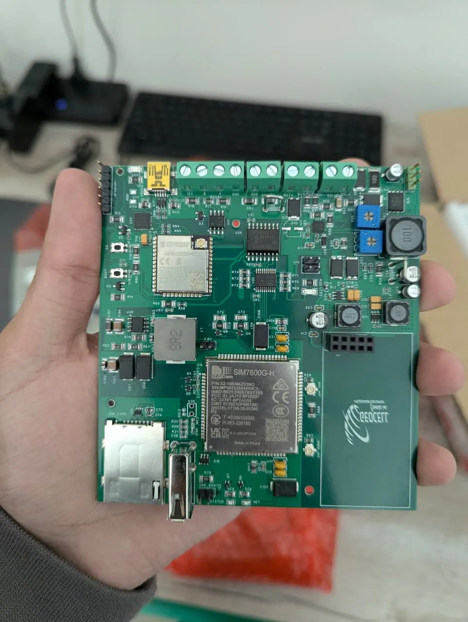 Custom controller PCB held in hand during bring-up